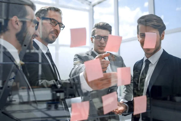 I colleghi di lavoro leggono appunti appiccicosi su vetro — Foto Stock