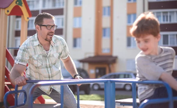 Lycklig far leker med liten pojke på lekplatsen — Stockfoto