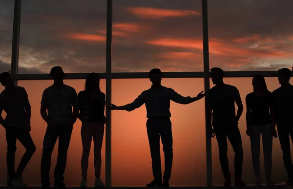 Leader and a group of young people standing near a large window — Stock Photo, Image