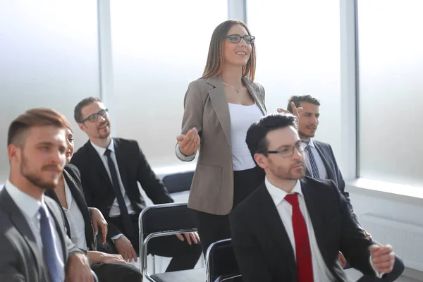 Mujer de negocios hace una pregunta de pie en la sala de conferencias — Foto de Stock