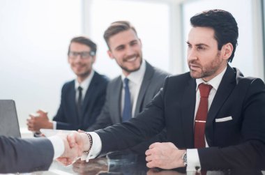 Ofis masasında el sıkışan iş adamları.