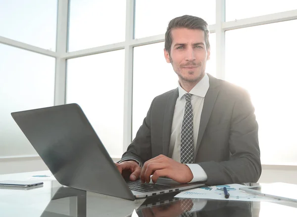 Sorridente empresário sentado em sua mesa — Fotografia de Stock