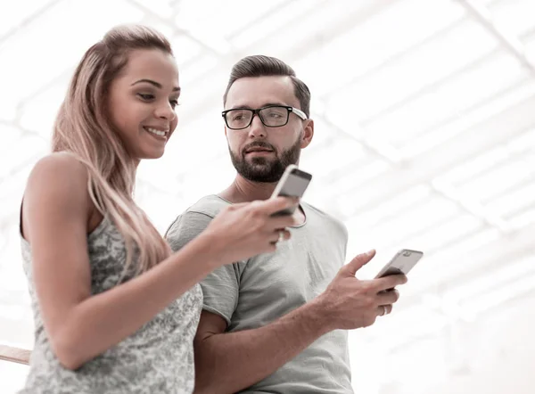 Ungt par titta på skärmarna av sina smartphones — Stockfoto