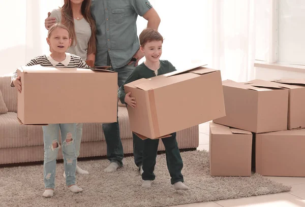 Родители с детьми переносят коробки в новую квартиру — стоковое фото