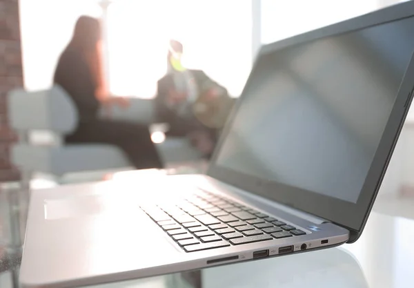 Concéntrate en el portátil sobre la mesa. Personas borrosas en el fondo . — Foto de Stock