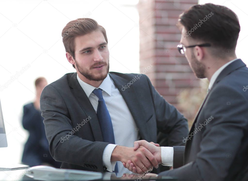Image of two young businessmen interacting at meeting in office