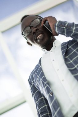 Alt görüntü. Gülümseyen iş adamı cep telefonuyla konuşuyor.