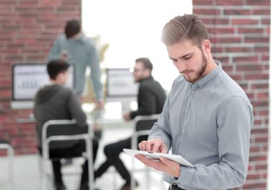 Ofisteki tablette çalışan neşeli bir iş adamının resmi.