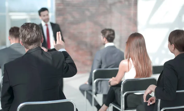 Membro do pessoal levanta a mão em uma conferência para responder a uma pergunta — Fotografia de Stock