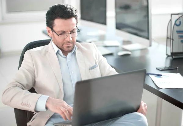 Empresário usando um laptop sentado em sua mesa — Fotografia de Stock
