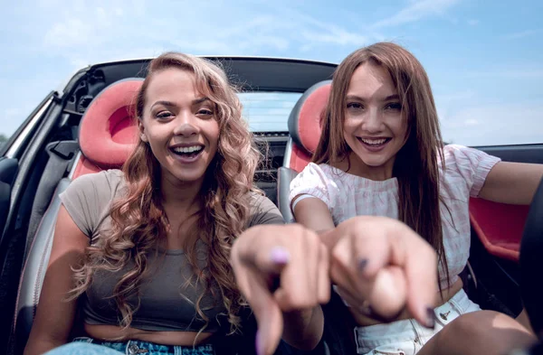 Dos chicas felices sentadas en el coche y apuntándote —  Fotos de Stock