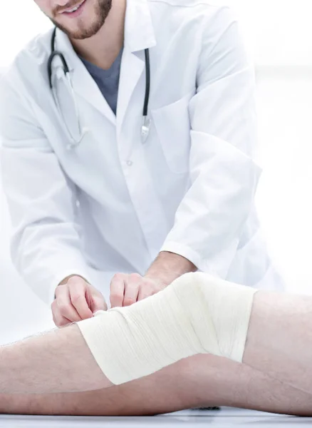 Médico olhando para a bandagem na perna pacientes — Fotografia de Stock