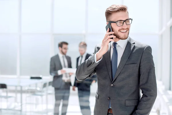 Hombre de negocios con teléfono móvil de pie junto a la oficina del Banco — Foto de Stock