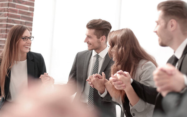 Business group in a circle holding hands indoors