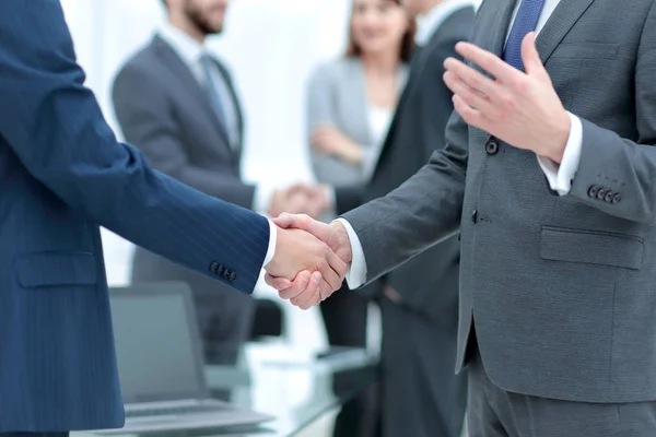 Business partners handshaking over business objects on workplace — Stock Photo, Image