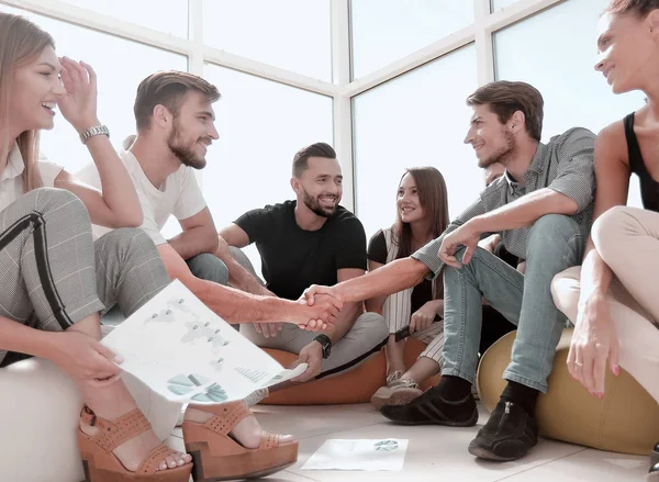 Amigos apertando as mãos, sentado no chão no novo escritório — Fotografia de Stock