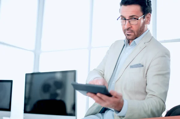 Affärsman som innehar en miniräknare när du sitter vid sitt skrivbord — Stockfoto