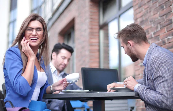 Geschäftsfrau spricht in Straßencafé mit Smartphone — Stockfoto