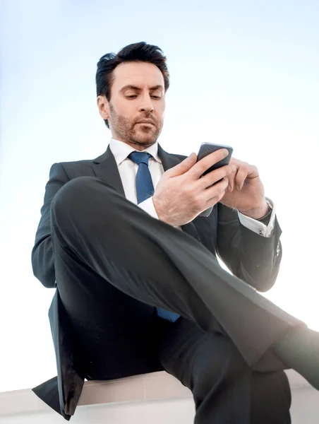 Bottom view.confident homem de negócios com telefone inteligente — Fotografia de Stock
