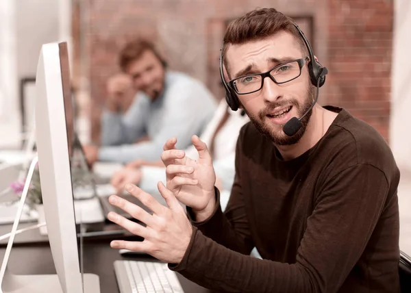 Az ember ül egy világos irodai számítógépek fejhallgatóval — Stock Fotó