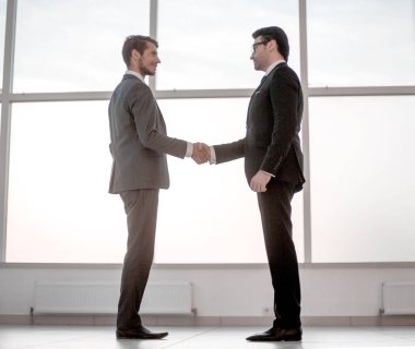 İşadamları büyük ofis pencere duran tokalaşın