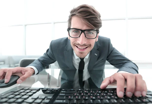 Grinning giovane in costume seduto alla scrivania e utilizzando la tastiera del computer — Foto Stock