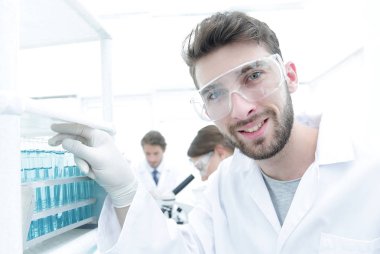 Bir örnek bir test tüpü yan bakarak genç erkek bilim adamı vie