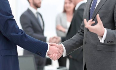 İş ortakları iş yerlerindeki iş eşyalarının üzerinden el sıkışıyor