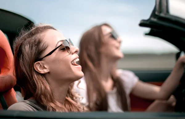 Dos chicas de moda viajan en un coche descapotable . — Foto de Stock