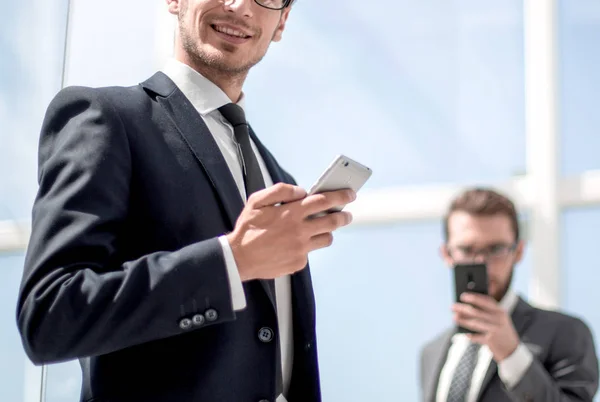 Homme d'affaires moderne avec un smartphone sur fond de bureau — Photo
