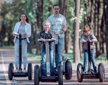 parkta bir elektrikli mini hoverboard sürme iki çocuklu aile.