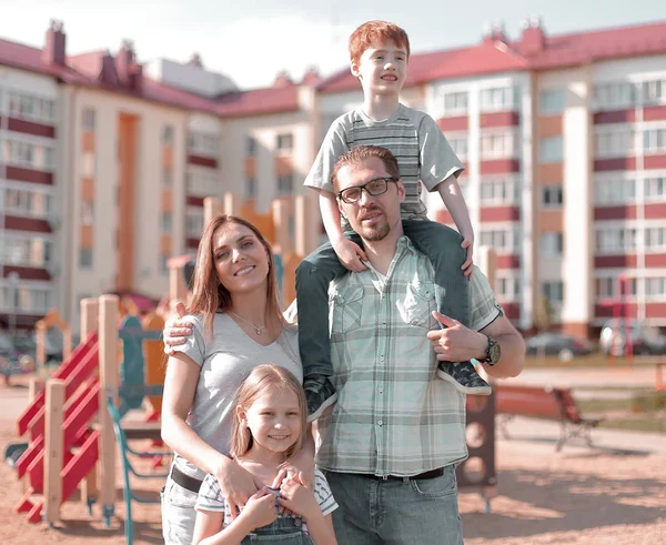 Ung familj stående på gården av en ny bostads byggnad — Stockfoto