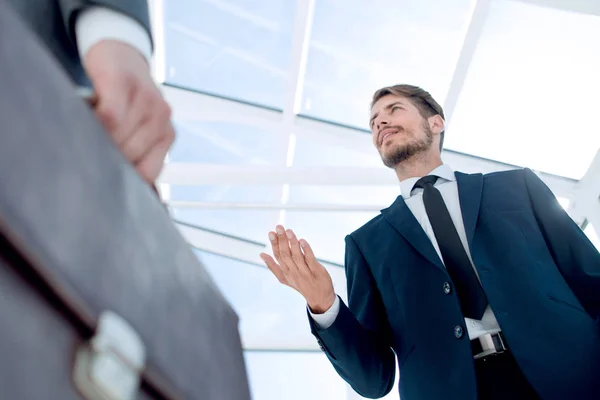 Unrecognizable businessman with suitcase close-up on a modern building background — Stock Photo, Image