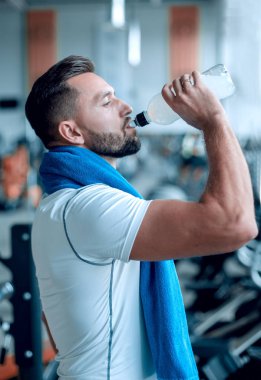 Trreadmill spor salonunda su şişe içki genç yetişkin adam.