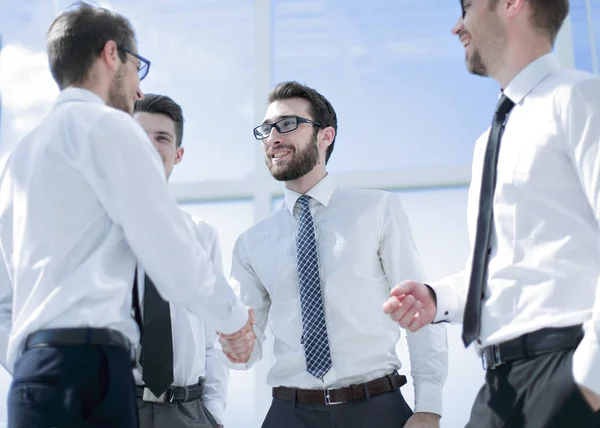 Zakenmensen schudden elkaar de hand terwijl ze op kantoor staan — Stockfoto