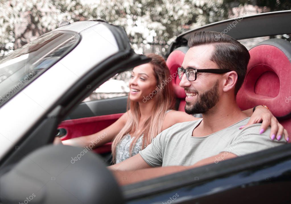 loving couple sitting in the front seat of a convertible car