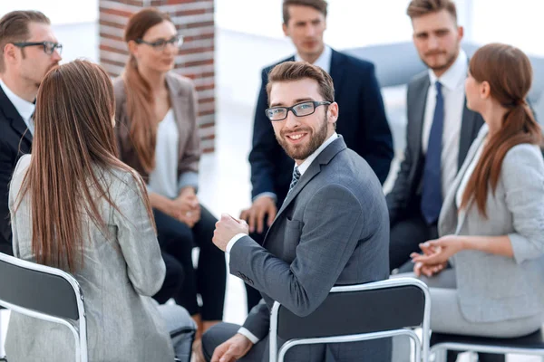 Jovem empregado sentado em um círculo de colegas — Fotografia de Stock