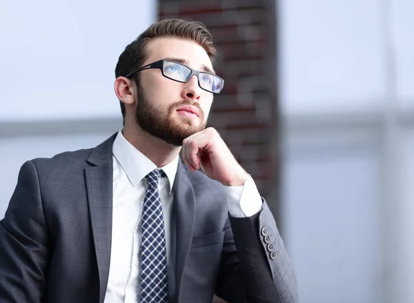 Knappe zakenman denkt, zittend op de bank in zijn kantoor — Stockfoto