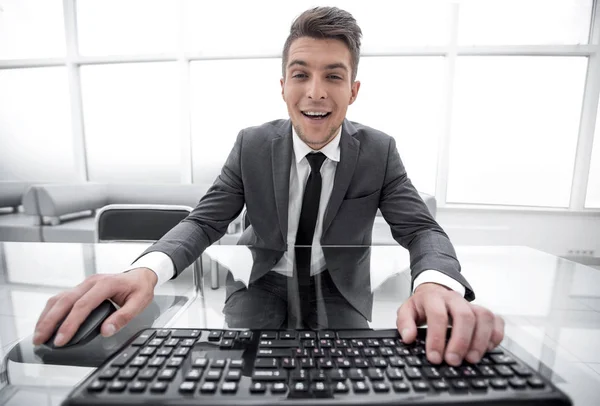 Casual businessman looks at the camera, keyboard — стоковое фото