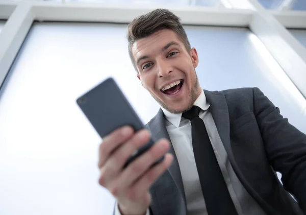 Glad affärsman med telefon tittar på kameran — Stockfoto