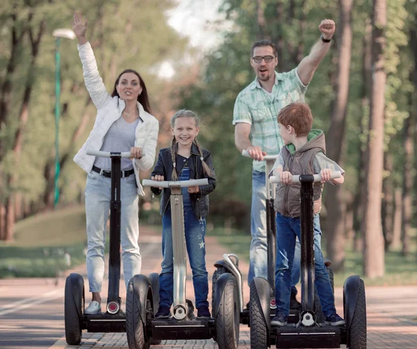 Modern familj rider en elektrisk mini hoverboard i parken — Stockfoto