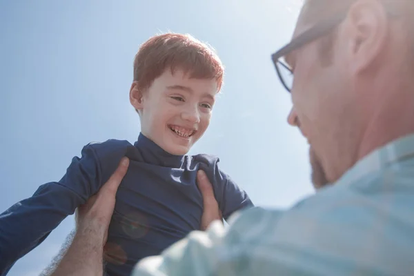 Gestileerde photo.a gelukkige zoon in zijn vaders veilige handen — Stockfoto