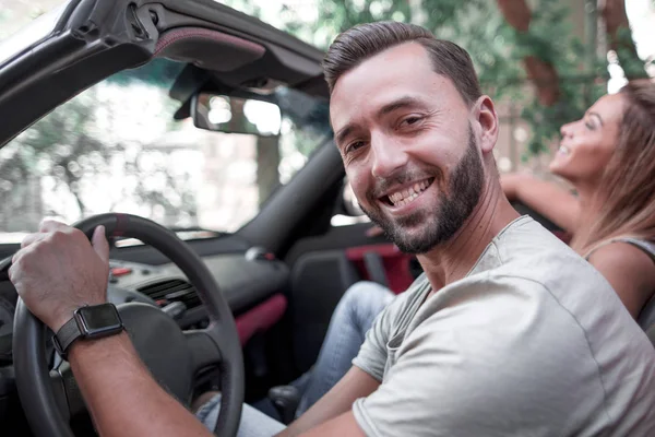 Close up.portrait de um homem sorridente sentado ao volante de um carro conversível — Fotografia de Stock