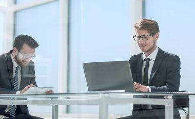 Masada oturan iki iş adamı konuşuyor.