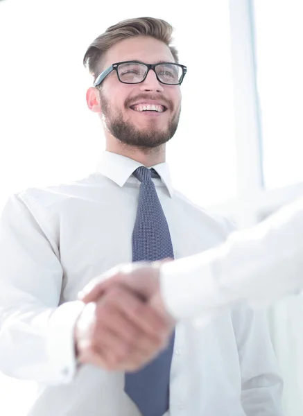 Крупним планом. усміхнений працівник тремтить рукою свого колеги — стокове фото