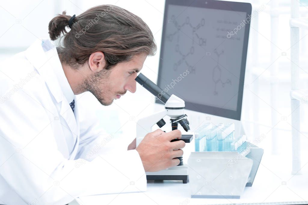 senior lab technician using microscope in laboratory