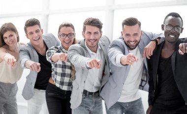 Bir grup insan kamerayı işaret ediyor ve gülümsüyor.