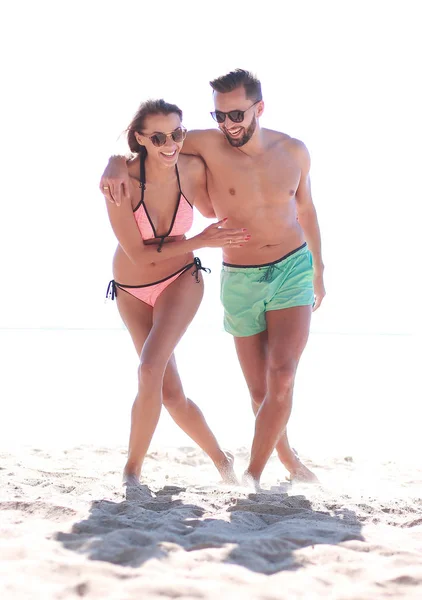 Pareja joven cogida de la mano y caminando en la playa. — Foto de Stock