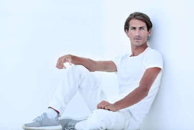 Beyaz bir duvar oturan üzgün genç adam