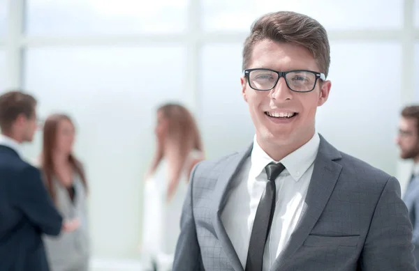 Sonriente joven hombre de negocios en borrosa oficina fondo . — Foto de Stock